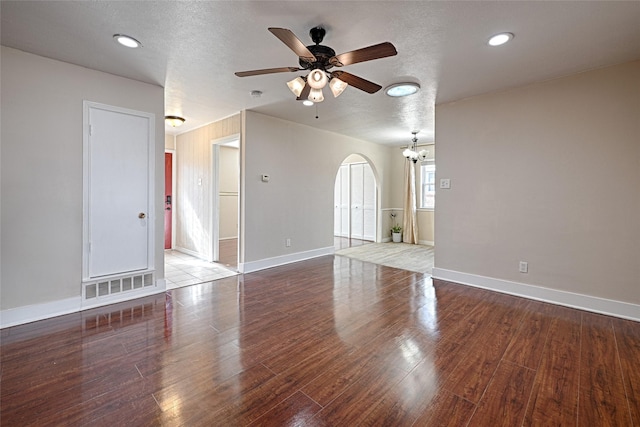 unfurnished living room with dark hardwood / wood-style flooring, ceiling fan with notable chandelier, and a textured ceiling