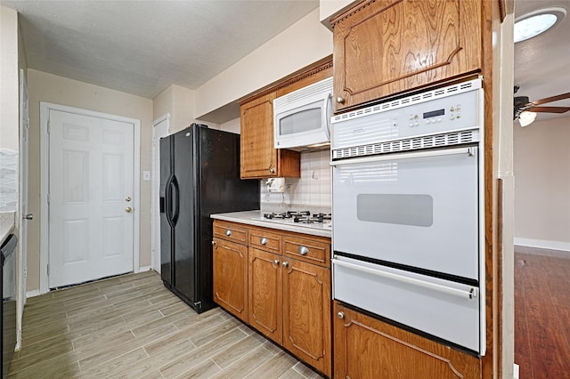 kitchen with backsplash, white appliances, ceiling fan, and light wood-type flooring