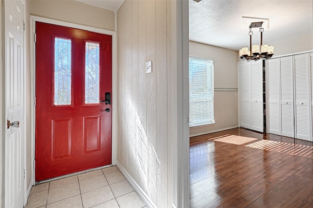 entryway featuring a textured ceiling, wooden walls, and a chandelier