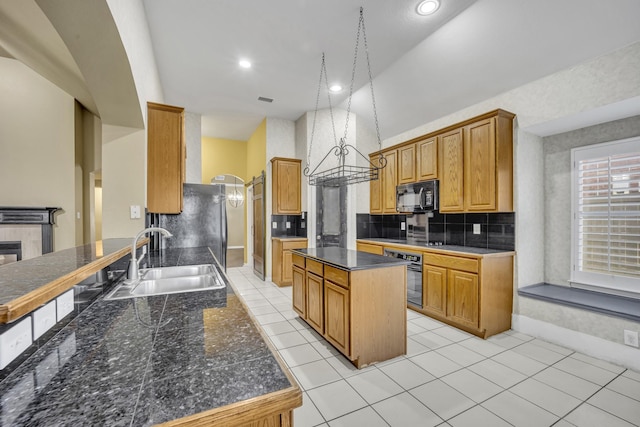 kitchen featuring sink, backsplash, a tiled fireplace, a center island, and black appliances