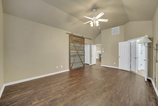 unfurnished living room with dark hardwood / wood-style floors, ceiling fan, lofted ceiling, and a barn door