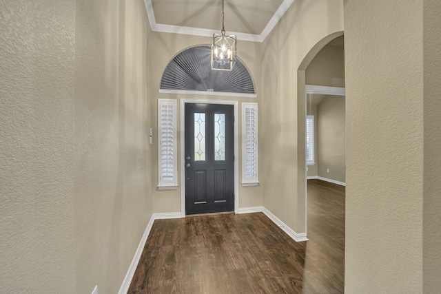 entrance foyer with a notable chandelier, crown molding, and dark hardwood / wood-style floors