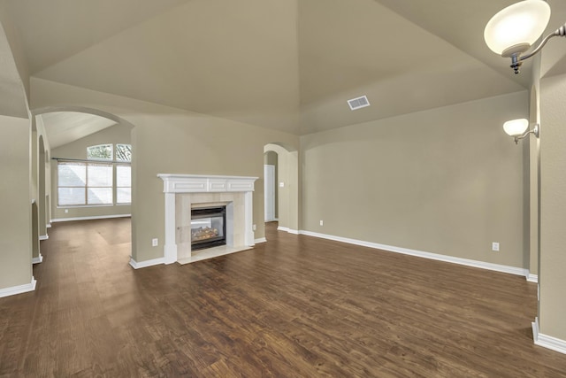 unfurnished living room with dark wood-type flooring, vaulted ceiling, and a tile fireplace