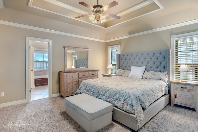 bedroom featuring connected bathroom, light colored carpet, ceiling fan, and a tray ceiling