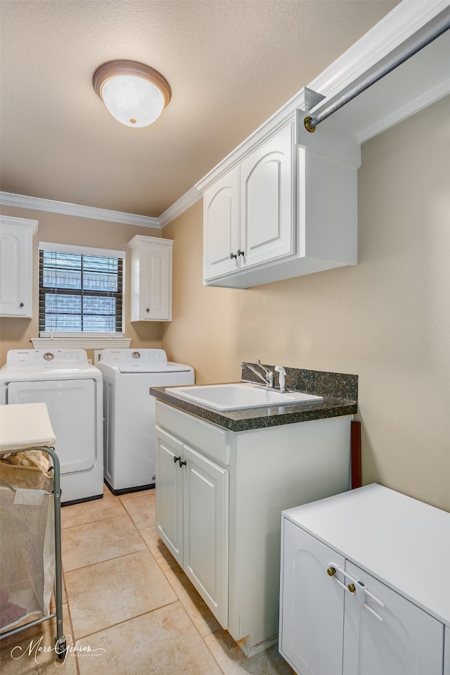 washroom featuring light tile patterned flooring, washing machine and clothes dryer, sink, crown molding, and cabinets