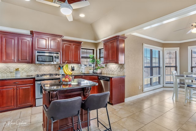 kitchen featuring a breakfast bar area, ceiling fan, appliances with stainless steel finishes, a center island, and tasteful backsplash