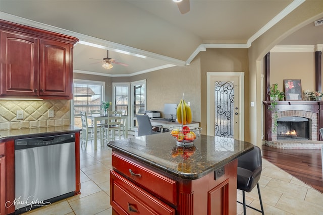 kitchen featuring a kitchen island, ornamental molding, stainless steel dishwasher, light tile patterned floors, and ceiling fan