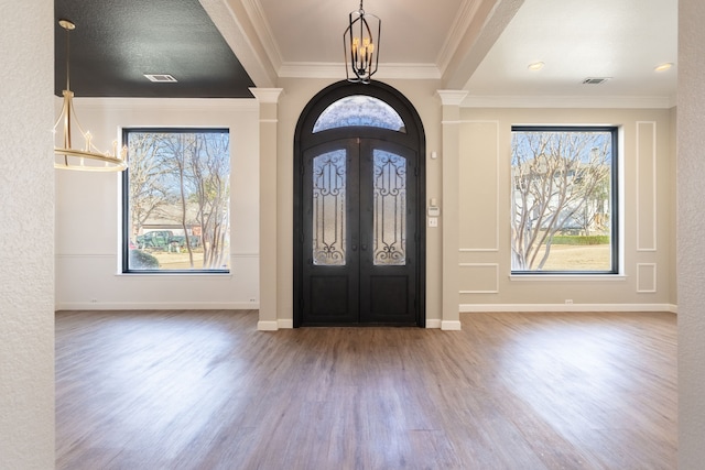 entryway featuring french doors, ornamental molding, decorative columns, and hardwood / wood-style flooring