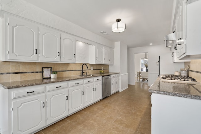 kitchen with sink, white cabinets, backsplash, dark stone counters, and stainless steel appliances