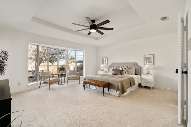 bedroom featuring light carpet, a tray ceiling, and ceiling fan