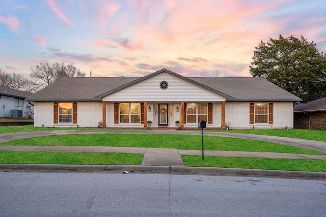 single story home with cooling unit and a lawn