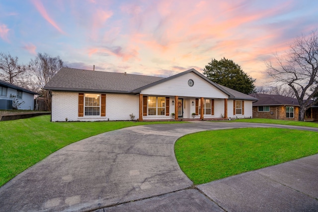 single story home with a porch, central AC unit, and a lawn