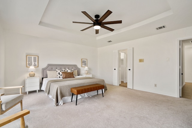 carpeted bedroom featuring ceiling fan and a raised ceiling