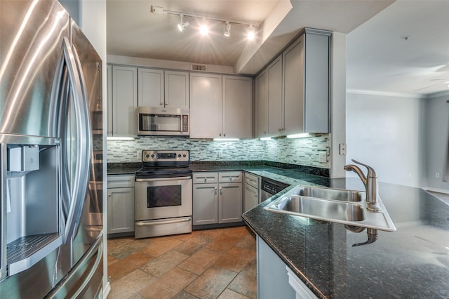 kitchen featuring sink, gray cabinetry, appliances with stainless steel finishes, dark stone counters, and decorative backsplash