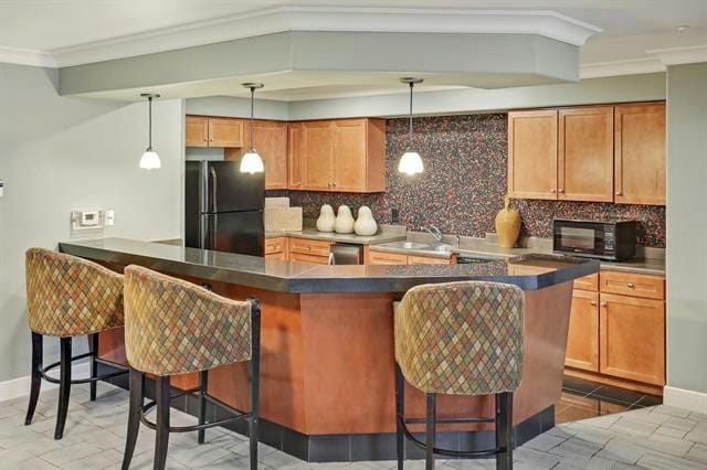 kitchen with hanging light fixtures, black appliances, kitchen peninsula, and a kitchen bar