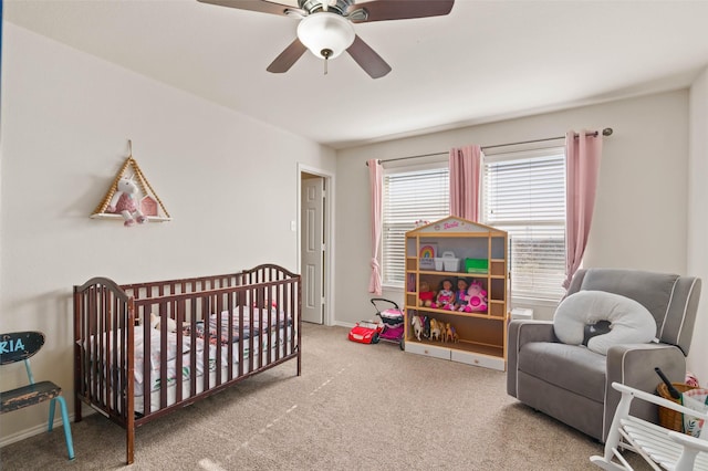 carpeted bedroom with a nursery area and ceiling fan