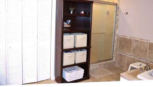 bathroom with a shower with door and tile walls