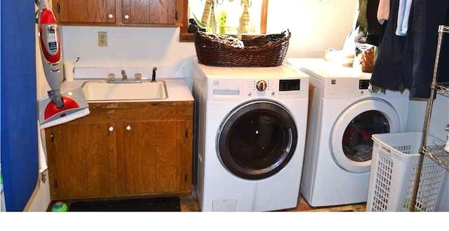 clothes washing area featuring cabinets, washer and dryer, and sink