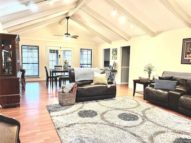 living room featuring lofted ceiling with beams, baseboards, light wood-style flooring, and ceiling fan