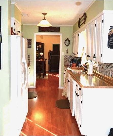 kitchen featuring white cabinetry, sink, white refrigerator, stainless steel counters, and dark wood-type flooring