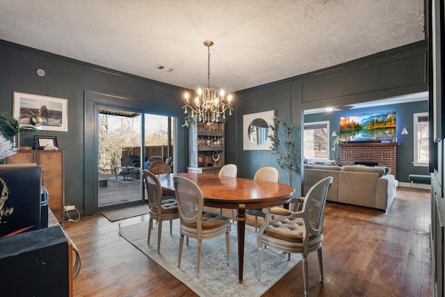 dining room with crown molding, hardwood / wood-style floors, a fireplace, and a textured ceiling