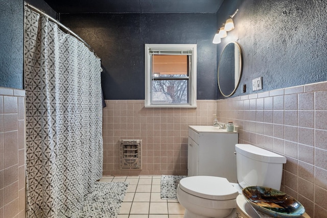 bathroom with toilet, tile patterned flooring, and tile walls