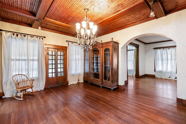 spare room with a notable chandelier, beam ceiling, wooden ceiling, and dark hardwood / wood-style floors