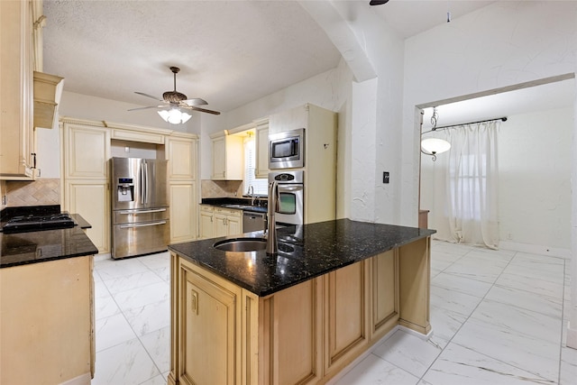 kitchen with sink, ceiling fan, appliances with stainless steel finishes, dark stone countertops, and backsplash