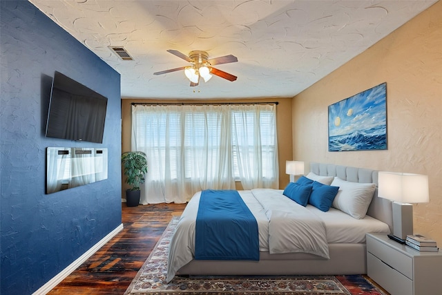 bedroom featuring dark wood-type flooring, ceiling fan, and a textured ceiling