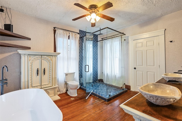 bathroom with hardwood / wood-style floors, a textured ceiling, independent shower and bath, and toilet