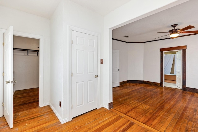 unfurnished bedroom with hardwood / wood-style floors, ceiling fan, and ensuite bath