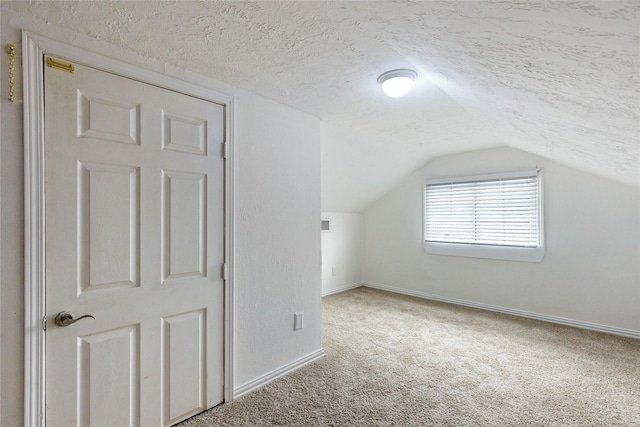 bonus room with vaulted ceiling, carpet floors, and a textured ceiling