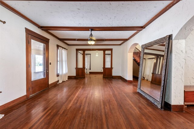 foyer entrance with ornamental molding, dark wood-type flooring, a textured ceiling, and beam ceiling