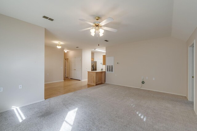 unfurnished room featuring ceiling fan, lofted ceiling, a healthy amount of sunlight, and light carpet