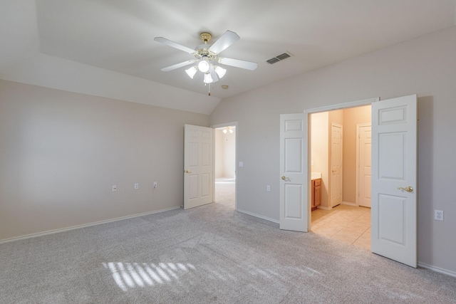 unfurnished bedroom with ceiling fan, ensuite bath, vaulted ceiling, and light carpet