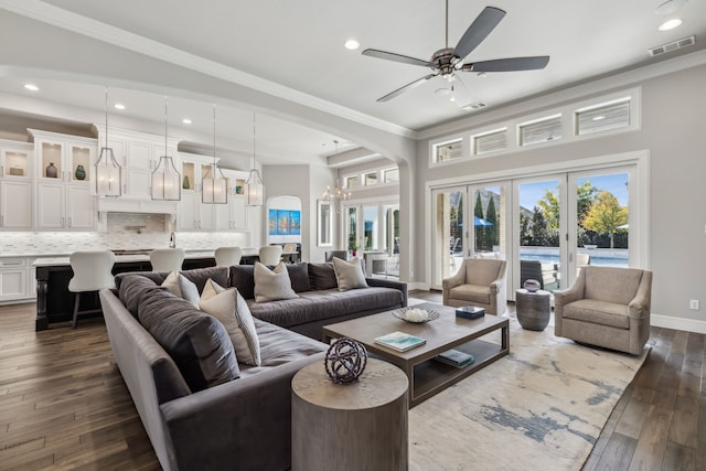 living room with crown molding, ceiling fan with notable chandelier, dark hardwood / wood-style floors, and french doors