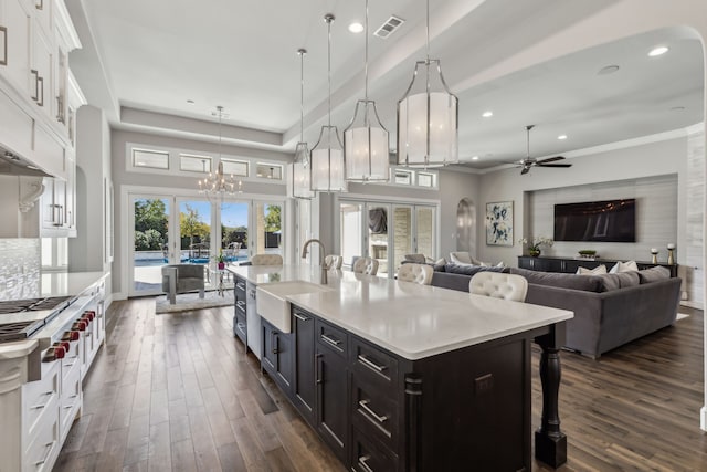 kitchen featuring sink, a breakfast bar area, white cabinetry, hanging light fixtures, and a kitchen island with sink