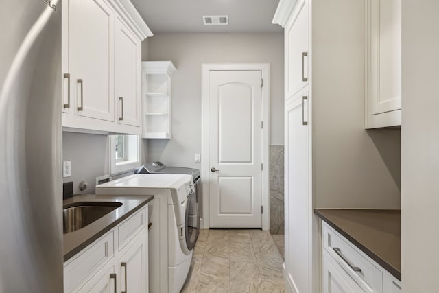 laundry area with separate washer and dryer, sink, light tile patterned floors, and cabinets