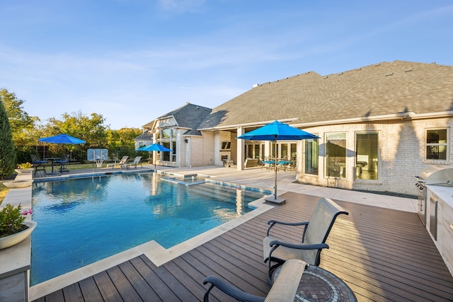 view of pool with an outdoor kitchen, a deck, grilling area, and a jacuzzi