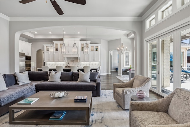 living room featuring ornamental molding, sink, ceiling fan with notable chandelier, and light hardwood / wood-style floors