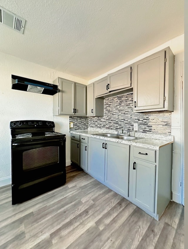 kitchen with sink, gray cabinetry, light wood-type flooring, electric range, and range hood