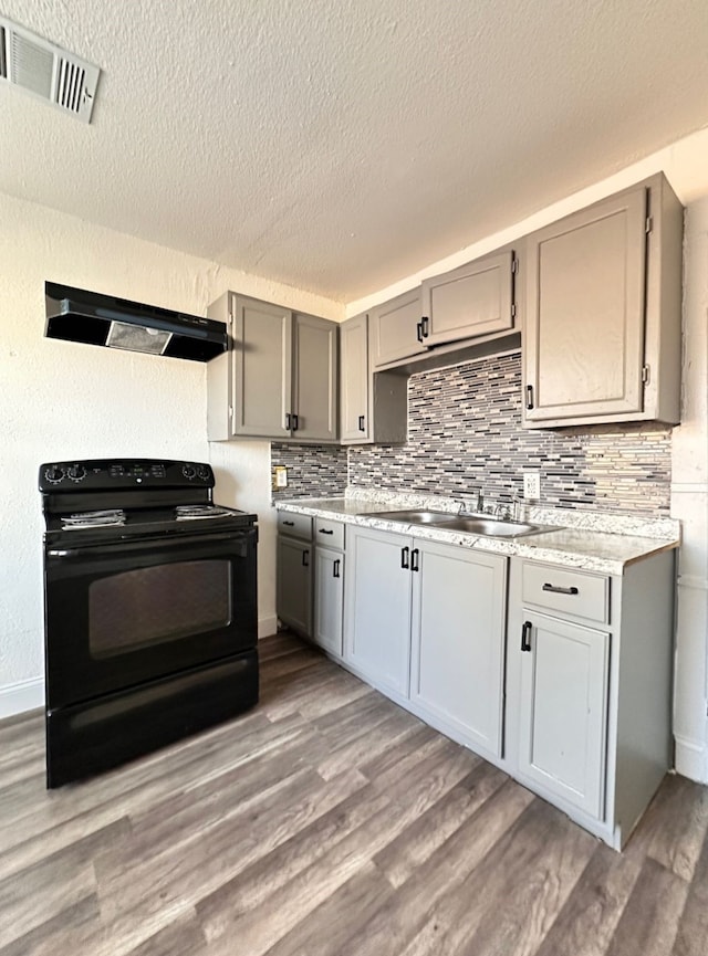 kitchen featuring sink, dark wood-type flooring, gray cabinetry, range hood, and black range with electric cooktop