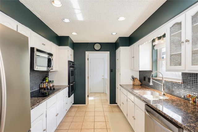 kitchen featuring white cabinetry, sink, stainless steel appliances, and dark stone counters