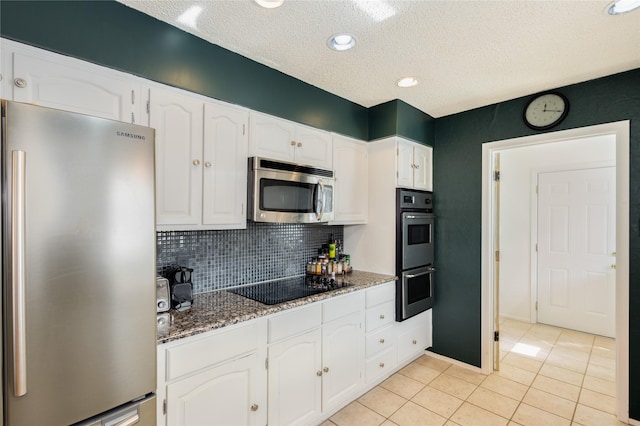 kitchen featuring white cabinetry, appliances with stainless steel finishes, light tile patterned flooring, and dark stone counters