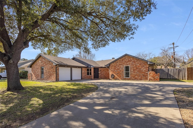 ranch-style home featuring a front lawn, fence, concrete driveway, an attached garage, and brick siding