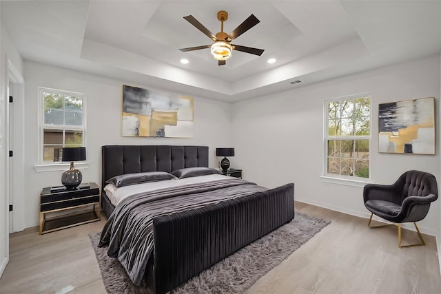 bedroom featuring multiple windows, a raised ceiling, and ceiling fan