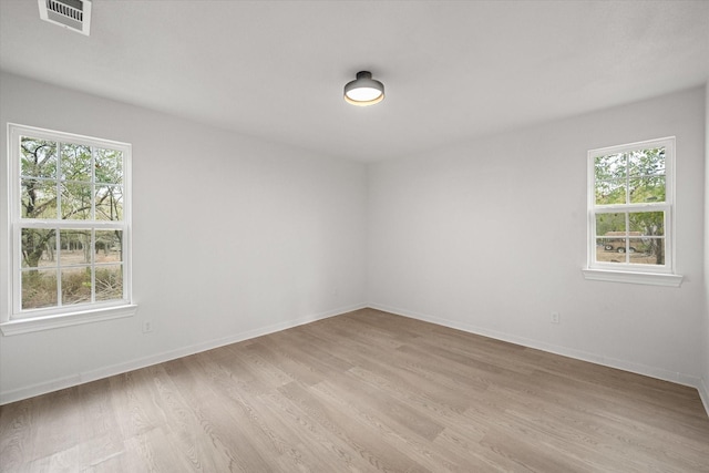 spare room featuring a healthy amount of sunlight and light hardwood / wood-style floors