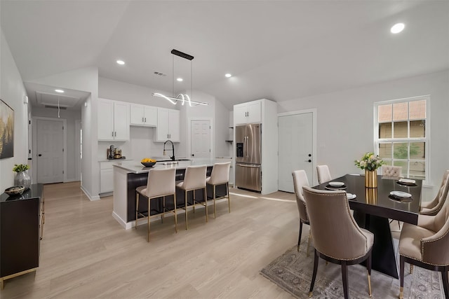 dining area with lofted ceiling, sink, and light hardwood / wood-style flooring