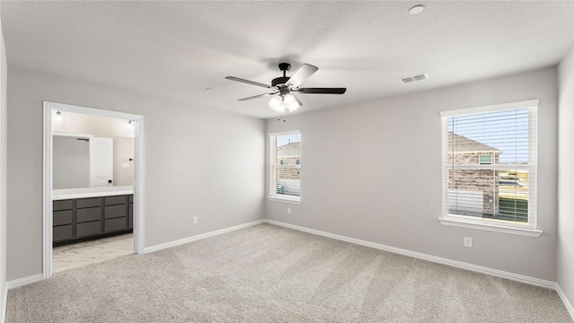 unfurnished bedroom with connected bathroom, light colored carpet, and ceiling fan