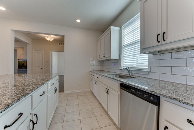 kitchen with light stone counters, sink, white cabinets, and dishwasher